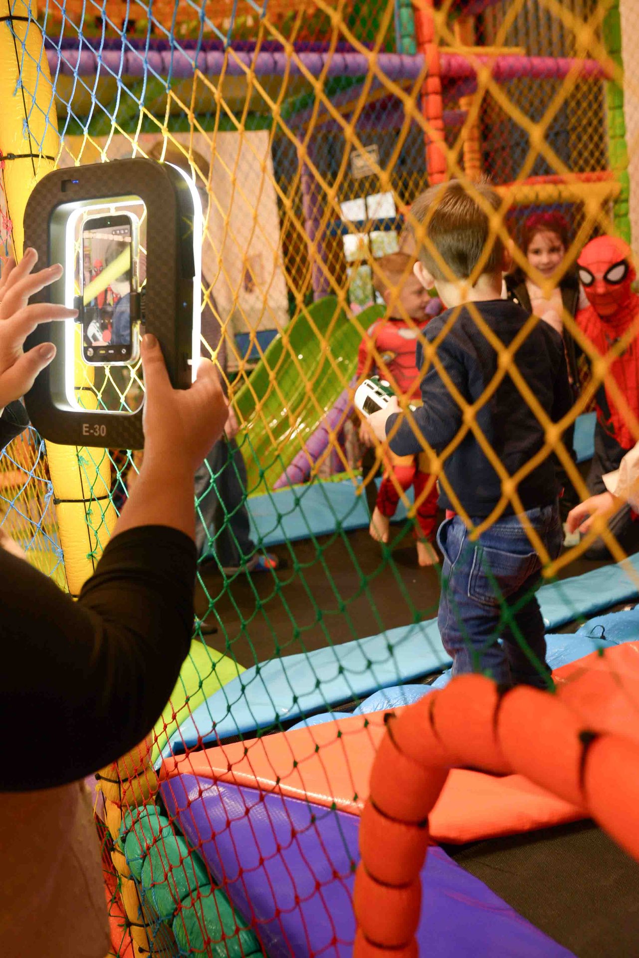 Mãos de Steffane operando celular com ring light durante a captação em tempo real de um evento infantil